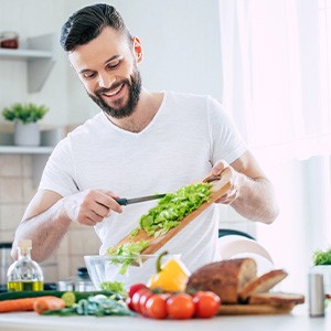 Man smiling while preparing salad in kitchen
