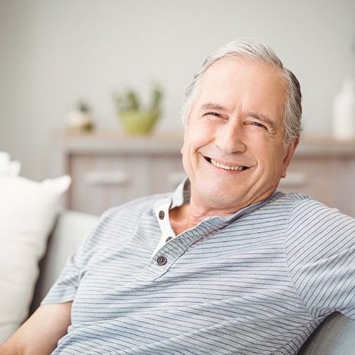 Older man smiling while seated on a couch