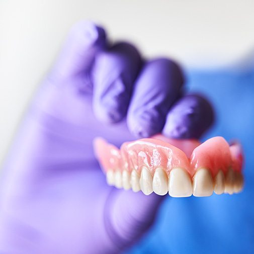 Dentist holding a full upper denture