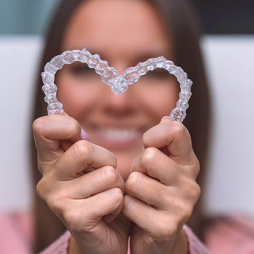 Woman holding Invisalign in the shape of a heart