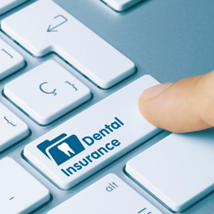 A finger clicking a computer key labelled ‘Dental Insurance’