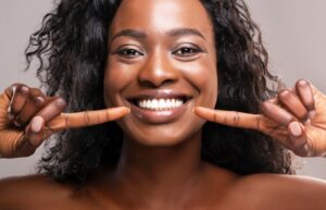 Woman smiling and pointing at her straight teeth