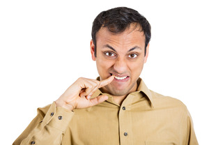 Man in button-up shirt pointing to food stuck between teeth